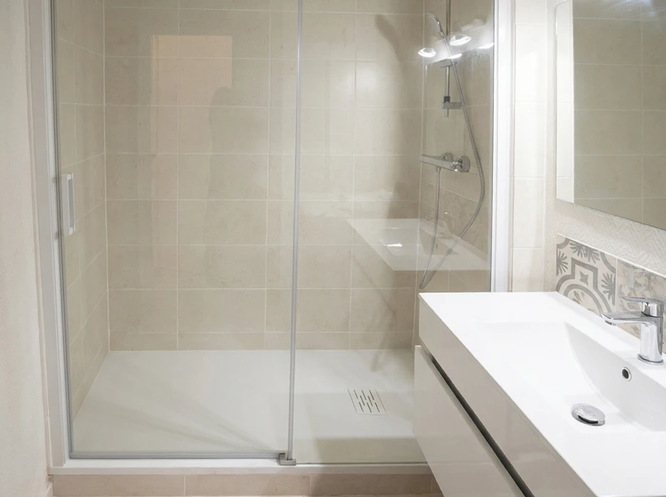 Salle de bain moderne avec douche à l'italienne équipée d'un receveur extra-plat blanc, paroi en verre coulissante, robinetterie thermostatique murale chromée avec douchette flexible