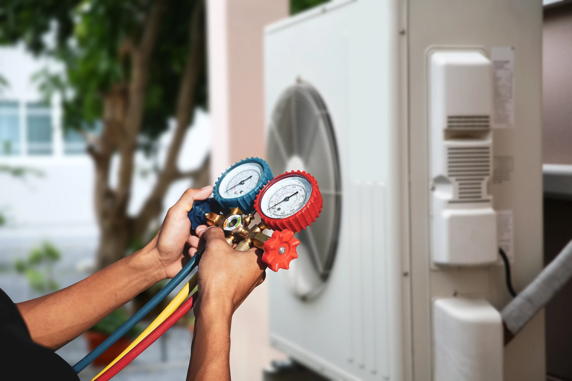 Technicien en climatisation travaillant à l'extérieur d'un bâtiment avec système de climatisation visible en arrière-plan