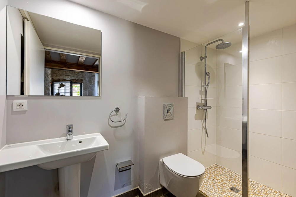 Salle de bain moderne avec vasque à poser noire brillante en verre trempé, montée sur meuble vasque bois grisé avec poignée noire
