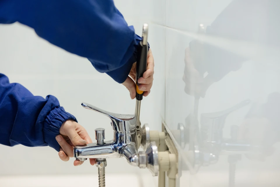 Salle de bain moderne avec baignoire encastrée, vasque ronde posée sur meuble suspendu noir, colonne de douche thermostatique avec douchette à main et pommeau de tête