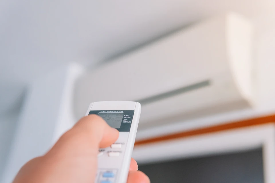 Technicien en salopette bleue effectuant la maintenance d'un radiateur à ailettes dans un intérieur résidentiel moderne