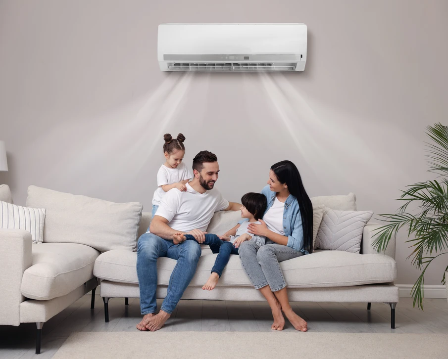 Extérieur résidentiel moderne avec unité de climatisation bi-split installée près d'une maison contemporaine aux façades sombre et claire, entourée de végétation et pelouse verte